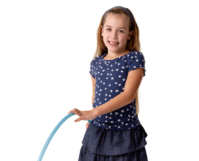 Cora, a person living with XLH, standing and smiling while holding a hula hoop
